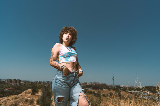 Woman with hands in pockets standing against clear sky