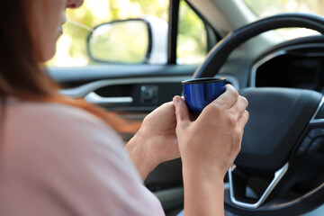 Woman with thermos cap driving car, closeup