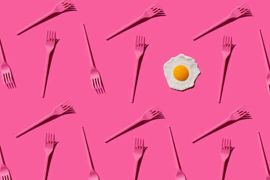 Pattern of pink plastic forks with single fried egg