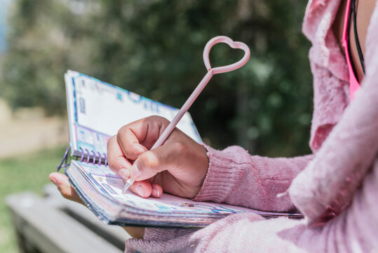 Close-up of young woman writing in diary at park