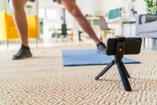 Tripod on floor with man exercising in background at home