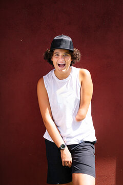 Teenage boy with mouth open standing against wall