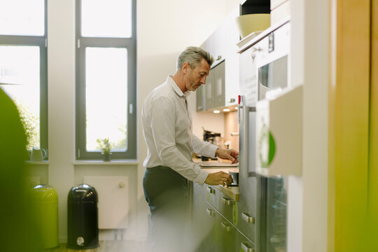 Man using coffee maker while standing at cafeteria