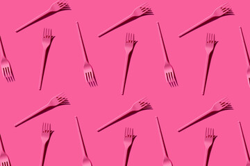 Pattern of pink plastic forks against pink background