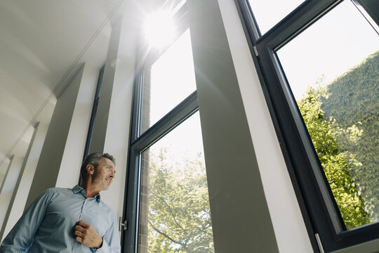 Businessman looking out of window while standing at office