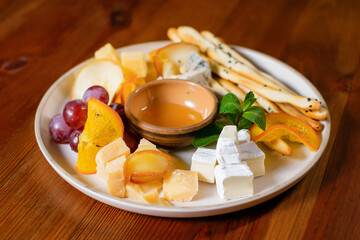 Fruit snack with grapes, cheese, croutons, honey, orange and pear garnished with mint.