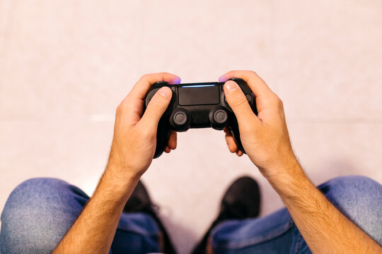 Young male gamer holding controller while playing at home