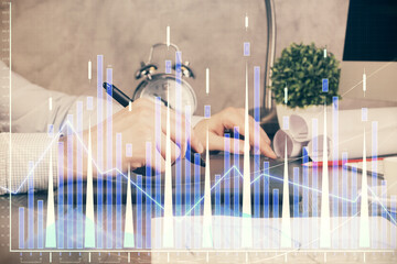 Double exposure of man's hands holding and using a phone and financial graph drawing. Analysis concept.