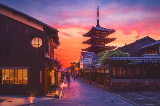 Ancient temple by traditional street against cloudy sky during sunset, Kyoto