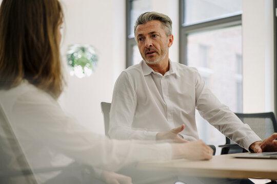 Businessman having discussion with woman while sitting at office