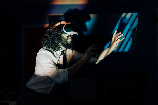 Man with virtual reality glasses playing in dark at home during pandemic