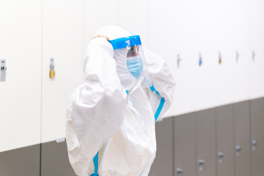 Man standing by locker wearing face shield in hospital