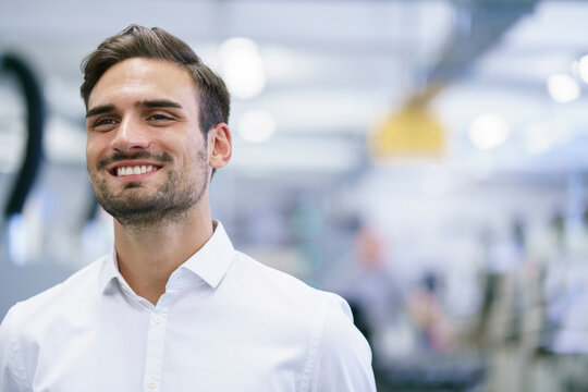 Smiling Young Male Professional Looking Away While Standing At Illuminated Factory