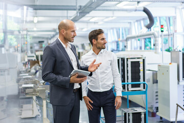 Confident male colleagues discussing while looking away at factory