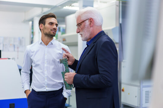 Senior manager discussing over circuit board with engineer at factory