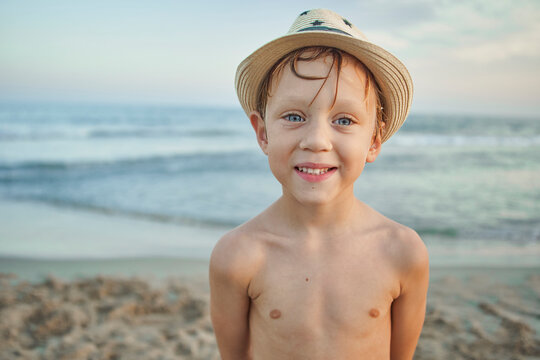 Boy smiling while standing against sea at beach