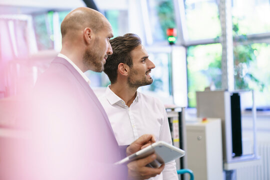 Male professionals discussing while looking away at factory