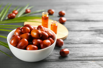 Palm oil fruits in bowl on grey wooden table, closeup