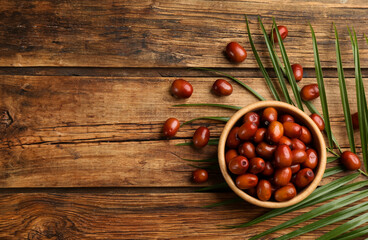 Palm oil fruits in bowl on wooden table, flat lay. Space for text