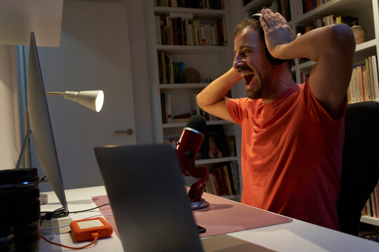 Mid adult man shouting on microphone while headphone sitting at home