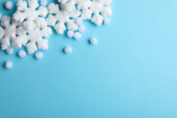 Beautiful snowflakes and decorative balls on light blue background, flat lay. Space for text