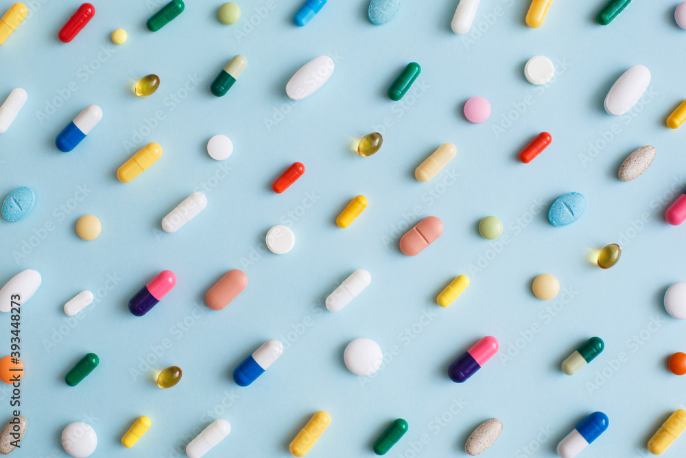 Wall mural Creative layout of colorful pills and capsules on blue background. Minimal medical concept. Pharmaceutical, Covid-19 or Coronavirus. Flat lay, top view