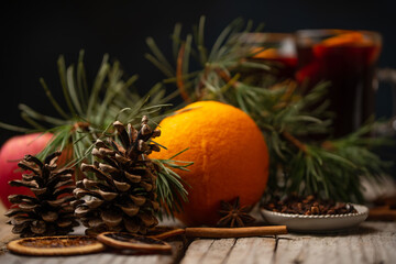 Appetizing christmas composition with juicy orange, spruce cone and branch on glasses with mulled wine background. fragrant spices. Festive mood.
