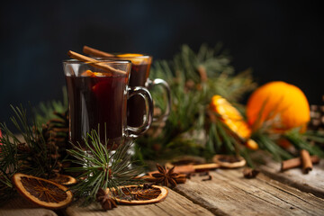 Appetizing christmas composition glasses of mulled wine on spruce cone and branch background....