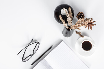 Directly above view - White desk, pen, note pad, pine cone, candle holder, eyeglasses, and coffee. Copy Space.