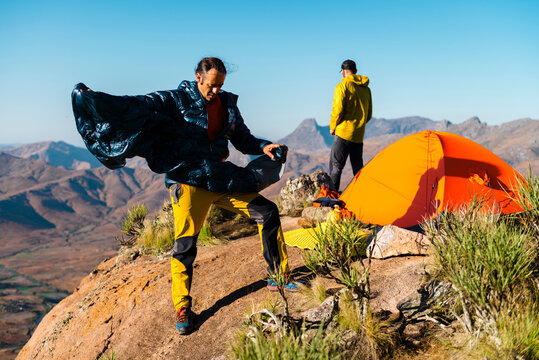 Male hikers coordinating the camp near tent on mountain peak