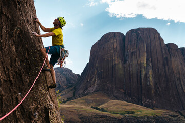 Male mountaineer leading pitch climbing on cliff in nature