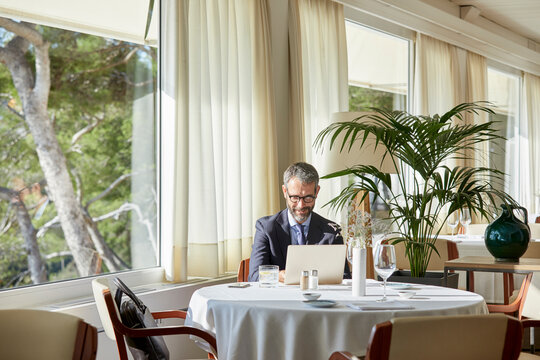 Businessman sitting by the restaurant table working on laptop