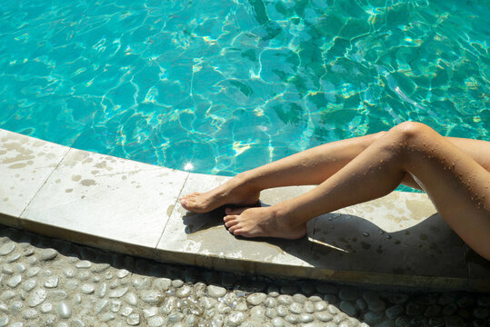 Crop woman's legs near swimming pool.