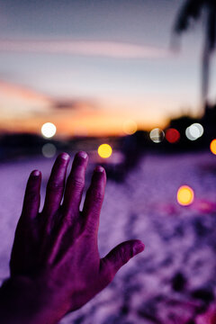 Hand of a man in a beach at night with lights
