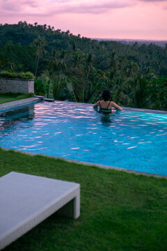 Girl stay at sunset in swimming pool.