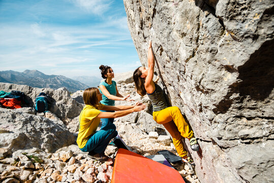 Group of three women climbers practicing bouldering in sunny day
