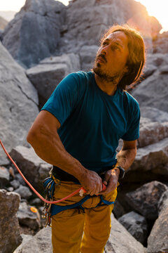 Exhausted ethnic mid aged male climber undo rope knot