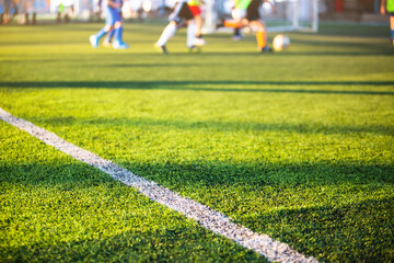 Selective focus to white lines on green artificial grass football fields with kid soccer player....