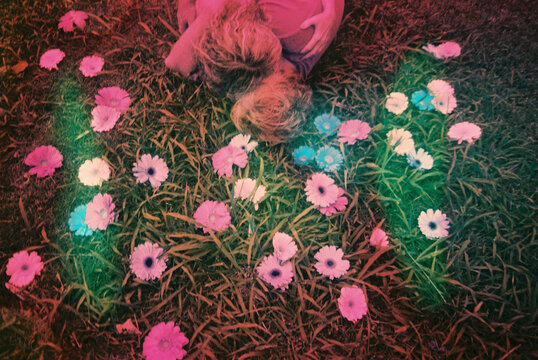 woman laying in grass with daisies and daises body painted on her skin