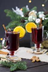 winter treats, a mugs of warm wine with an orange, and cookies, ingredients on a wooden brown...