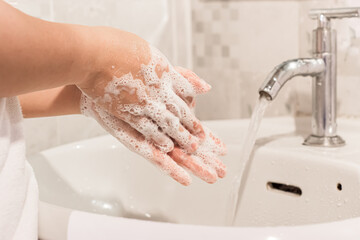 Female washes his hands with soap over a sink in the bathroom. Concept of hygiene treatment.