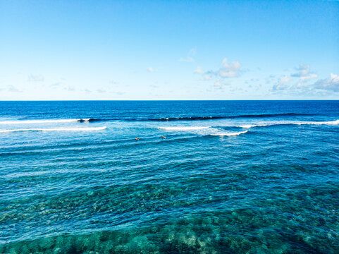 Aerial view of surfers rowing in tropical beach with reef