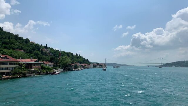 Footage of luxury houses and boats in upscale neighborhood called "Kandilli" by Bosphorus in Istanbul. It is a beautiful summer scene on cloudy summer day. Camera moves forward.