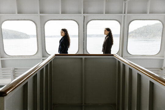 two young women standing on a ferry framed by windows