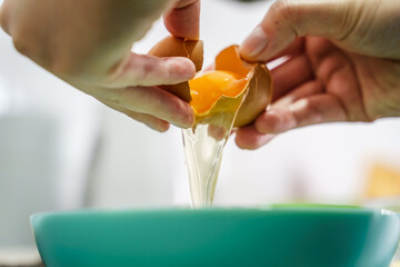 Close up on hands of unknown caucasian woman separating yolk of egg