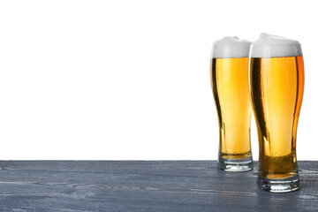 Glasses of tasty beer on blue wooden table against white background