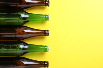 Bottles of beer on yellow background, flat lay. Space for text