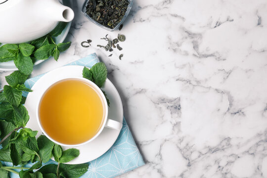 Fresh tea with mint on white marble table, flat lay. Space for text
