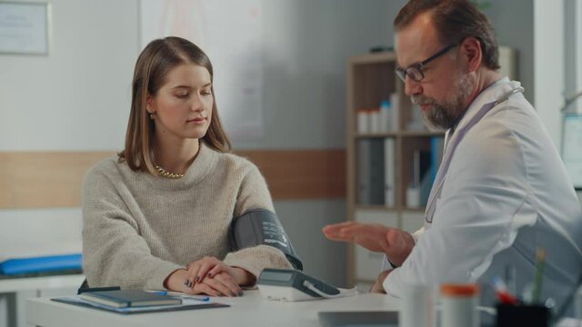 Doctor's Office: Physician Measures Blood Pressure of a Female Patient, Discussing Symptoms, Possible Prescription of Hypertension Drugs. Medical Health Care Specialist or Cardiologist Using Tonometer