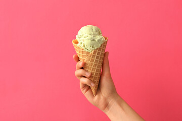 Woman holding waffle cone with delicious ice cream on pink background, closeup